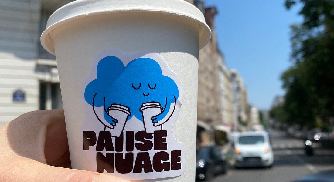 Un gobelet Pause Nuage avec son autocollant nuage, dans une rue de Paris